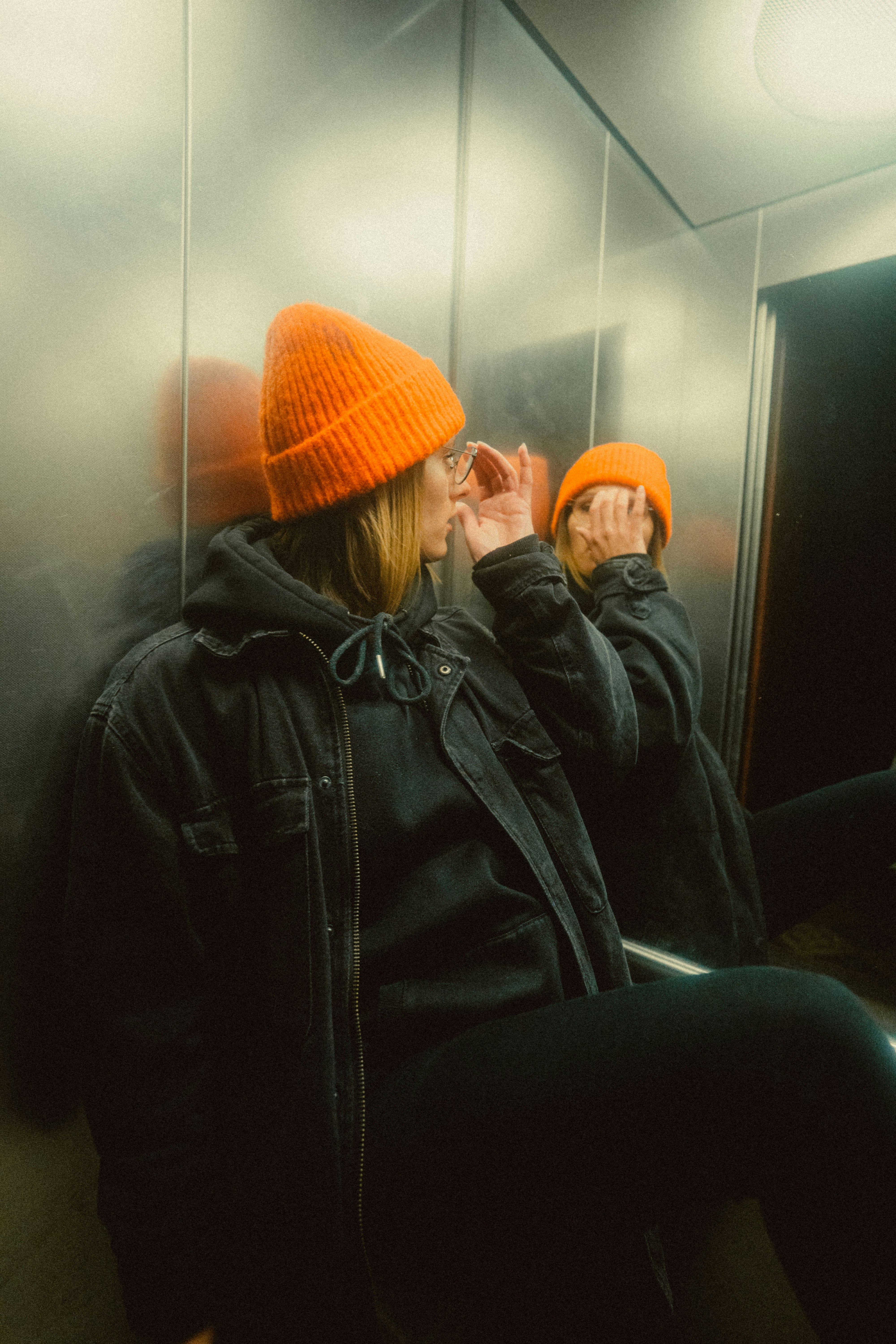 woman in black leather jacket and orange knit cap